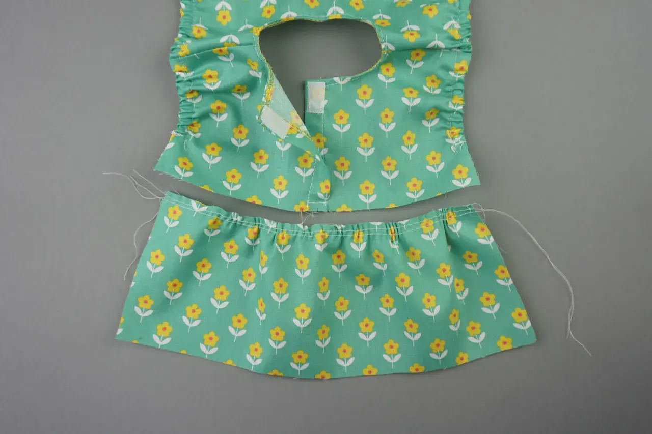Zwei Teile eines **Puppenkleid Schnittmusters** mit Blumenmuster: Oberteil mit Rüschen und Klettverschluss, Rockteil mit Gummizug.