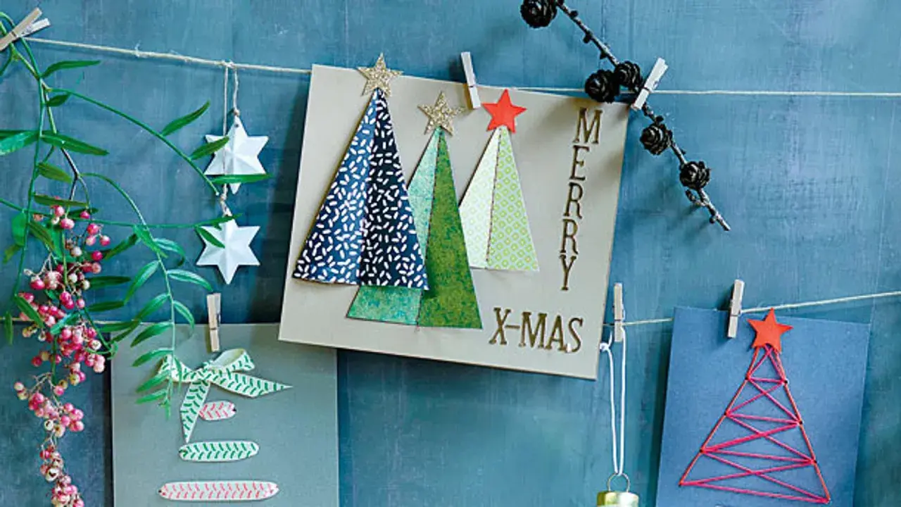 Moderne weihnachtskarten basteln: Karten mit Bäumen, Sternen und Schriftzug "Merry X-Mas" hängen an einer Schnur.