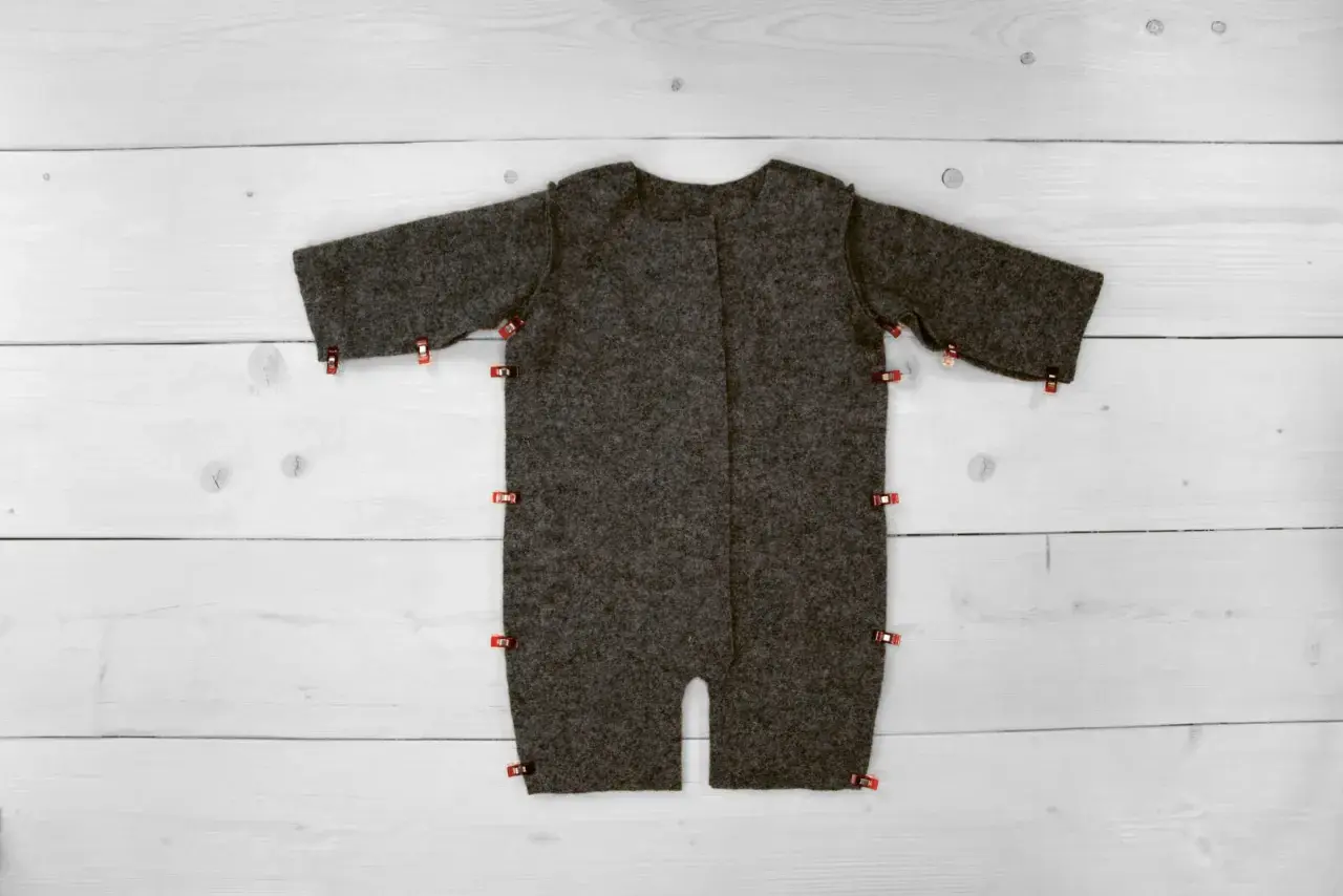 Graues Overall-Schnittmuster, bereit zum Nähen, mit roten Klammern fixiert. Ein tolles, **overall schnittmuster kostenlos** Projekt für DIY-Fans.