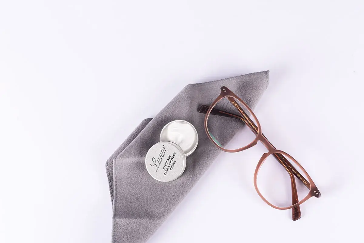 Brillenpflege: Acetatstoff waschen und mit Pflegemittel auffrischen. Brille und Tuch liegen bereit.