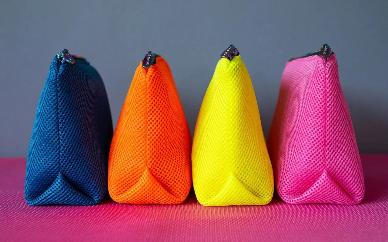 Vier bunte Netzbeutel in Blau, Orange, Gelb und Pink. Ein einfaches schnittmuster tasche, perfekt für Kosmetik oder Stifte.