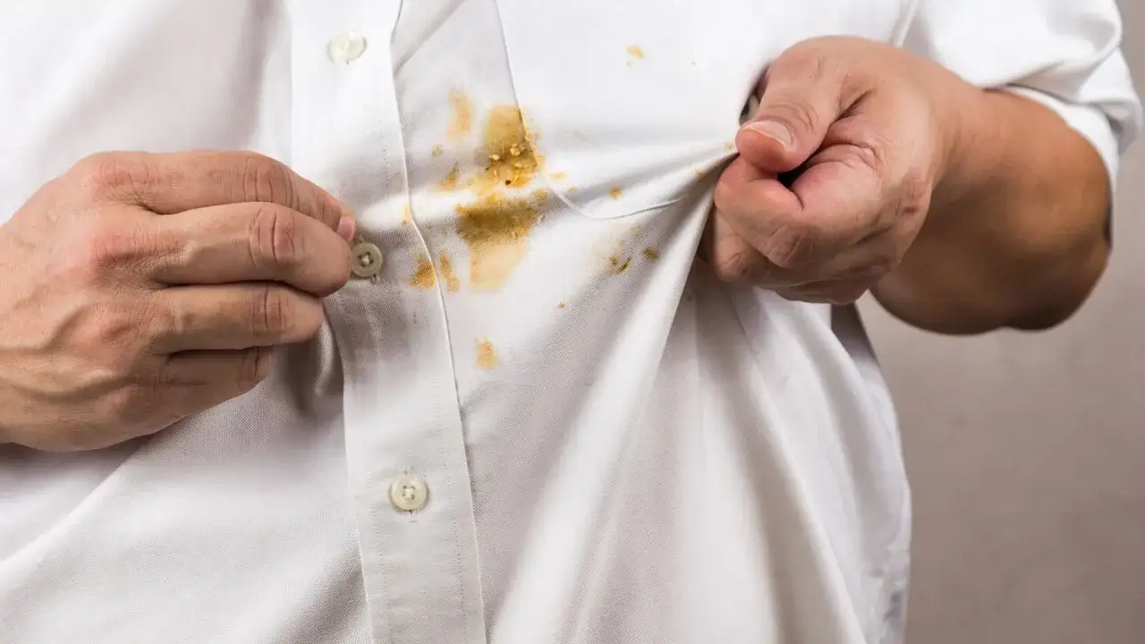Hände zeigen ein weißes Hemd mit hartnäckigen curry flecken entfernen.