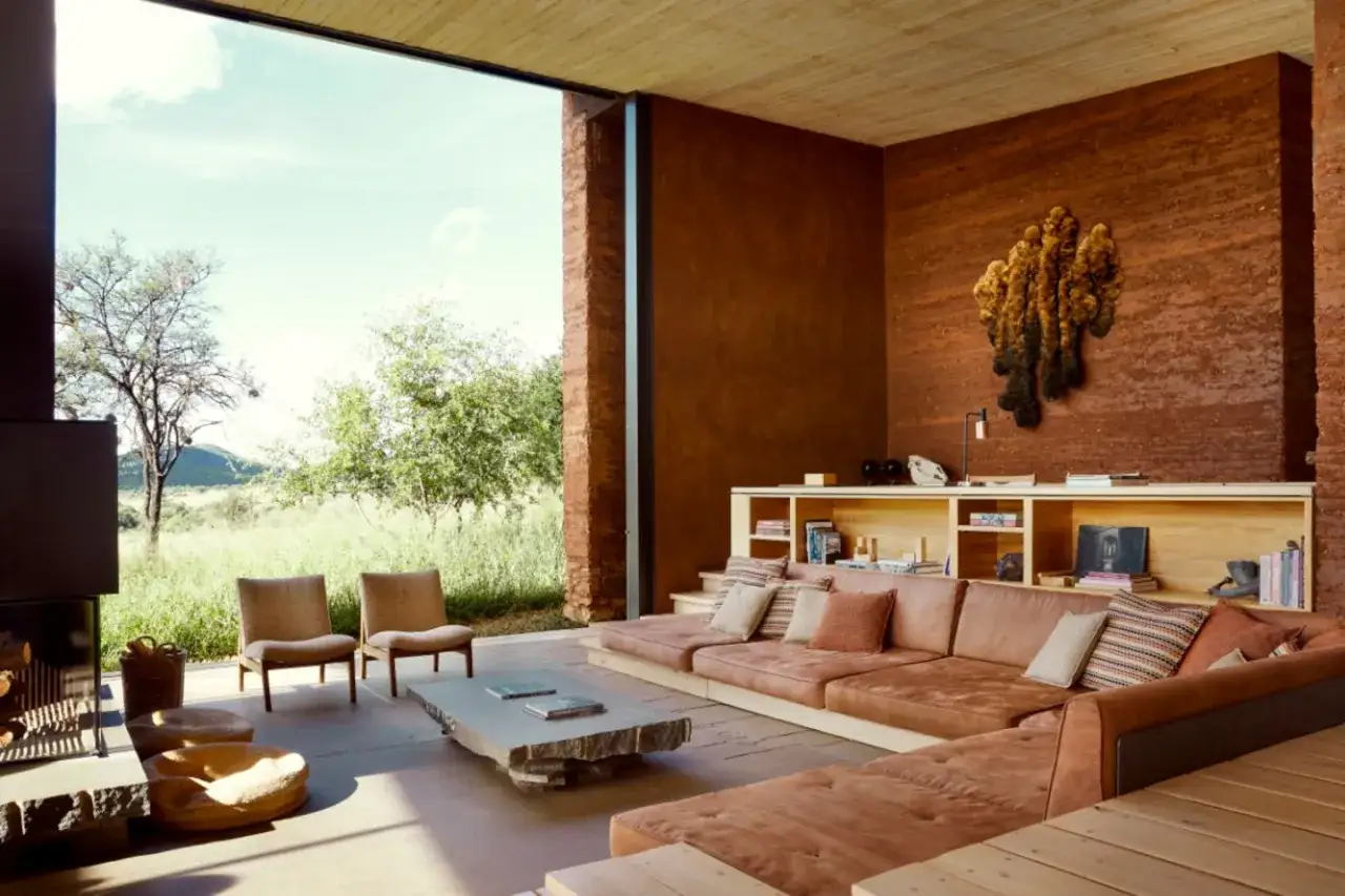Modernes haus einrichten: Wohnzimmer mit erdigen T&ouml;nen, gro&szlig;em Sofa und Blick ins Gr&uuml;ne.