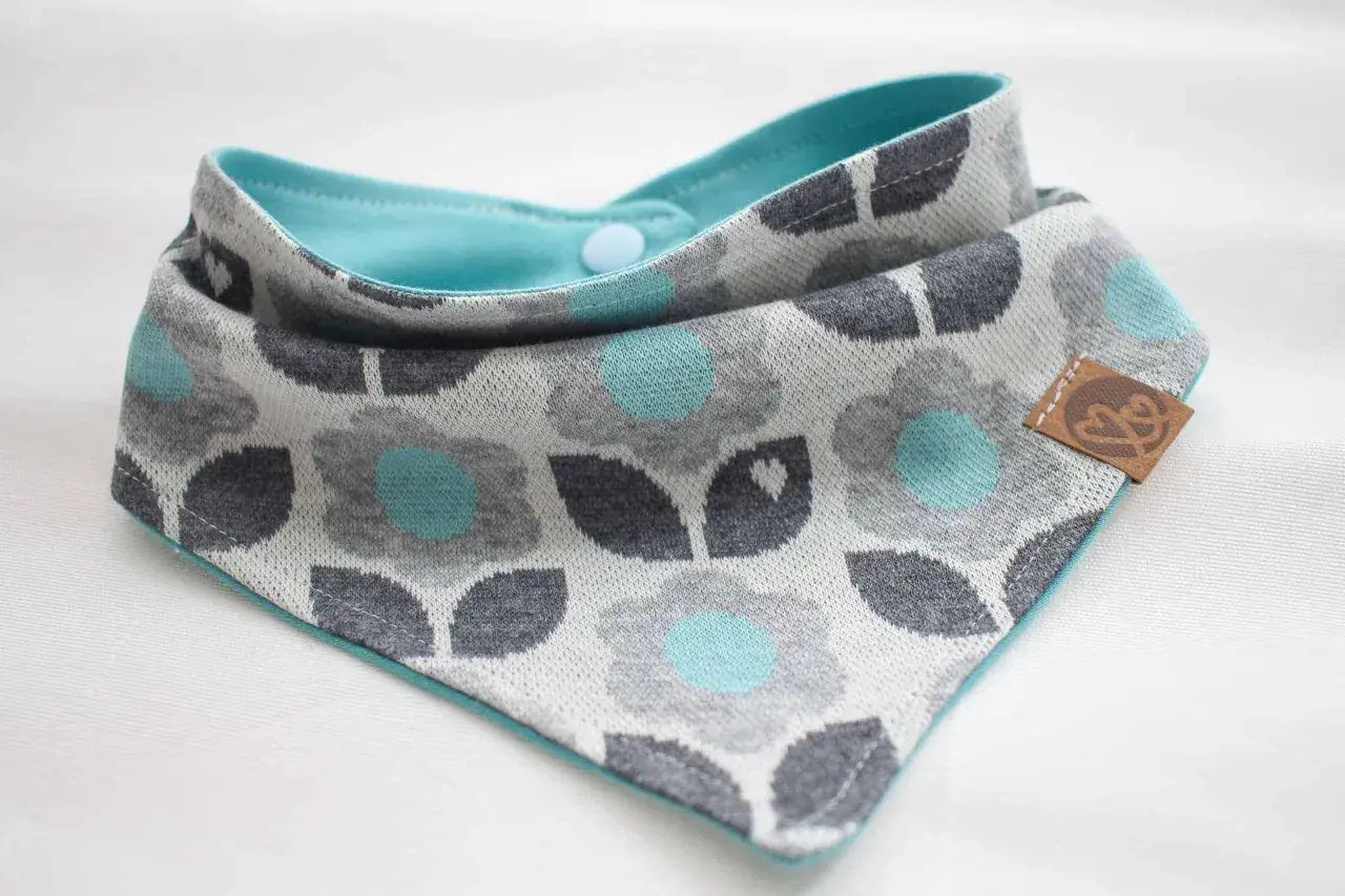 Süßes Halstuch für Babys mit Blumenmuster. Ein tolles Schnittmuster für ein Baby-Halstuch, das kleine Entdecker warm und trocken hält.