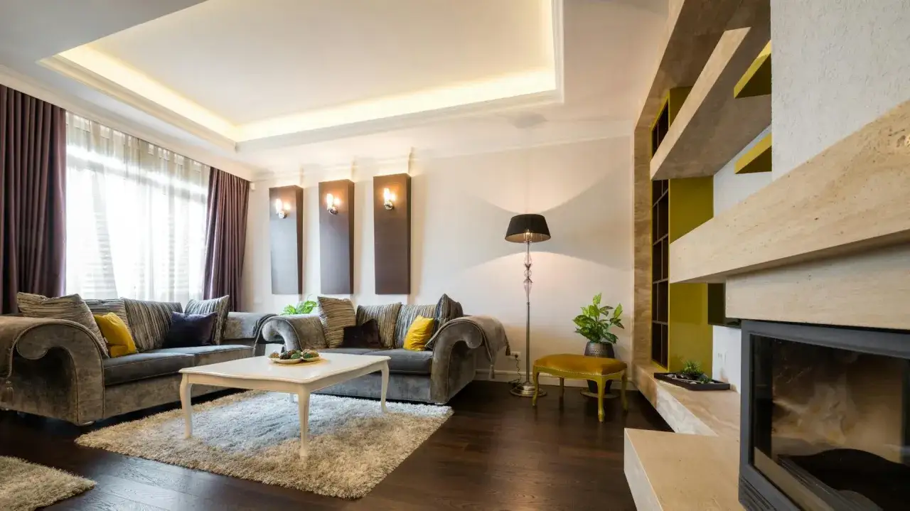Elegante wohnzimmer decke ideen mit indirekter Beleuchtung, die eine gemütliche Atmosphäre schaffen. Ein luxuriöses Sofa und ein Kamin laden zum Entspannen ein.