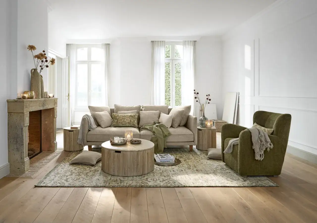 Gemütliches Wohnzimmer mit beigem Sofa, grünem Sessel und Kamin. Tolle wohnzimmer deko ideen für ein warmes Ambiente.