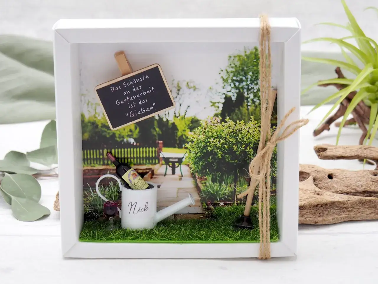 Ein liebevoll gestalteter Bilderrahmen mit Miniatur-Gie&szlig;kanne, Wein und Gartenger&auml;ten. Perfekt zum gutschein basteln f&uuml;r Gartenfreunde.