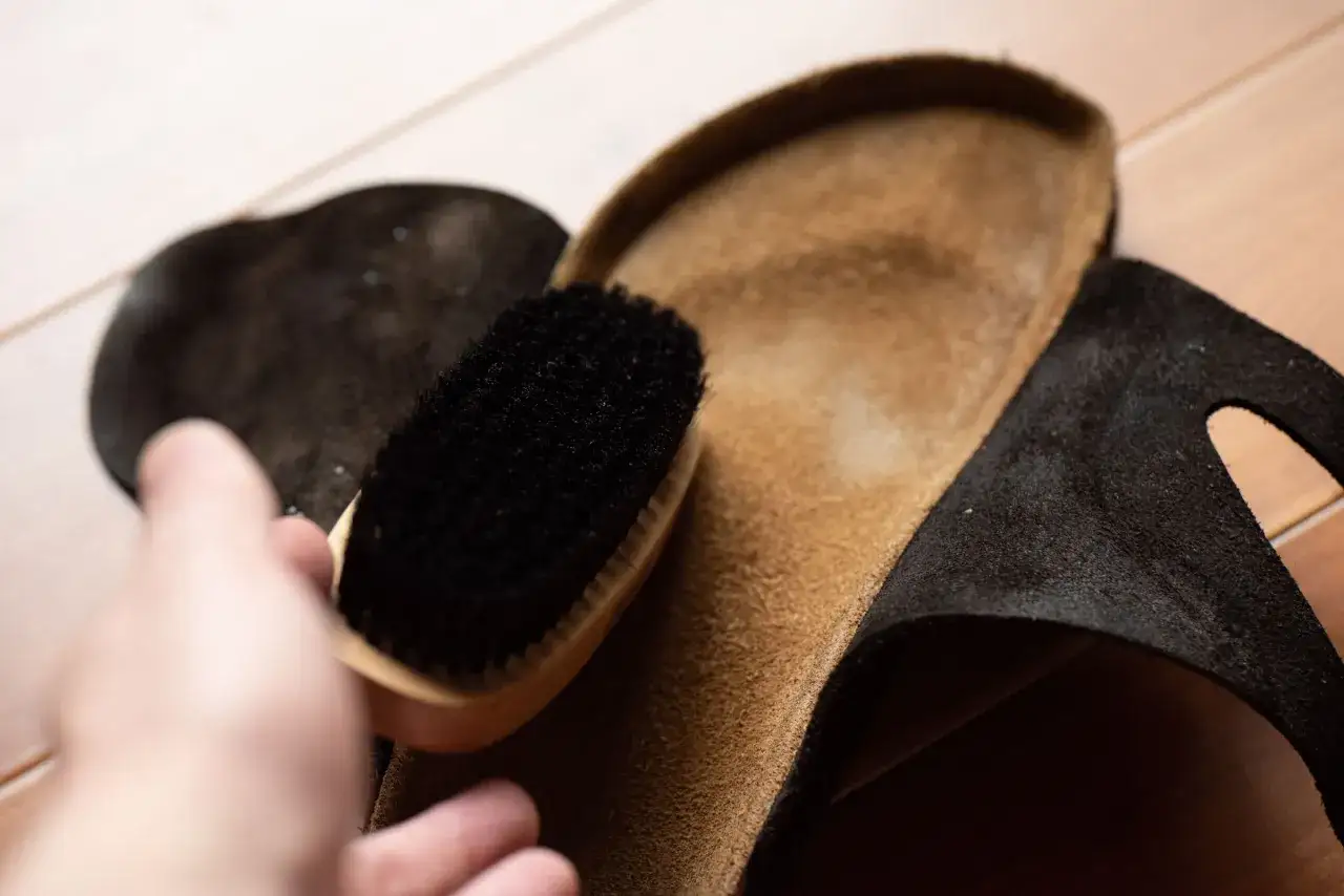 Hand b&uuml;rstet die Innensohle eines Birkenstocks, um sie zu reinigen.
