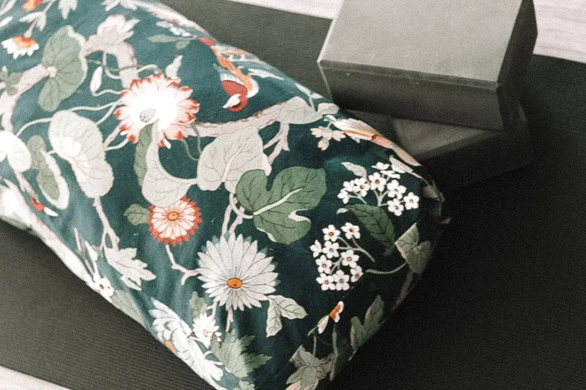 Blumengemustertes Yogakissen auf schwarzer Matte, daneben ein grauer Yogablock. Perfekt für dein DIY-Projekt: schnittmuster yogakissen kostenlos.