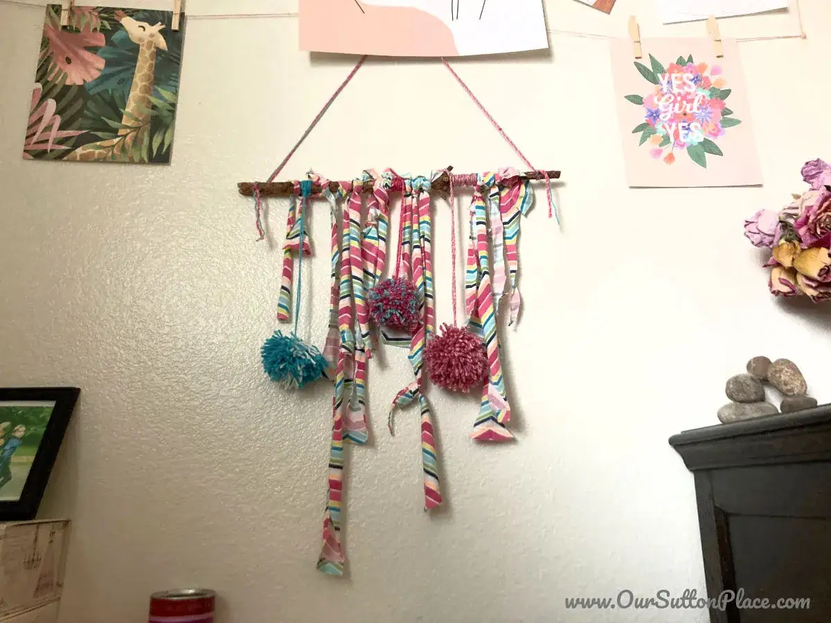 Upcycling-Idee: Buntes Wanddeko aus alten T-Shirts mit Pompons.