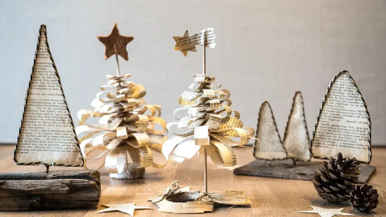Deko basteln mit alten Buchseiten: Kleine, handgefertigte Weihnachtsbäume aus Papier, verziert mit Sternen.