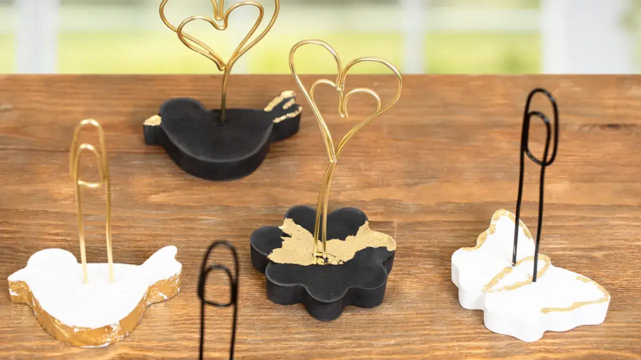 Kreative fotohalter selber machen: Vögel, Blumen und Schmetterlinge aus Beton mit Goldakzenten, die Fotos oder Karten halten.