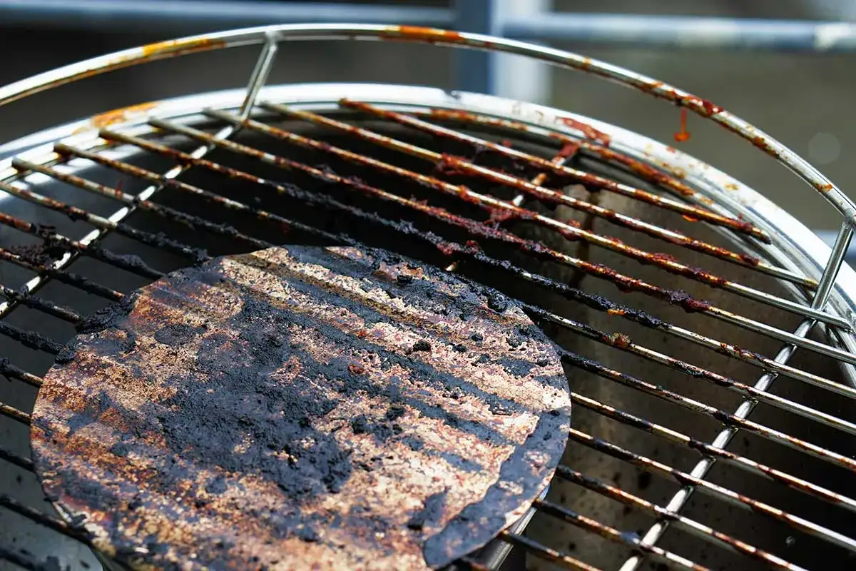 Ein eingebrannter Grillrost mit hartnäckigen Rückständen, der dringend eine Reinigung benötigt.