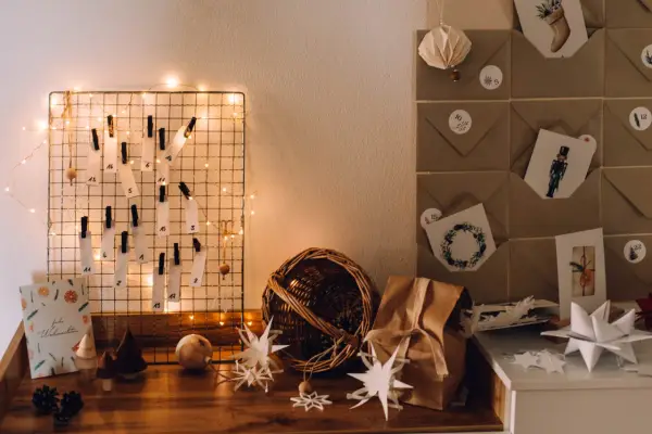 DIY Adventskalender basteln für Erwachsene: Ein Drahtgitter mit nummerierten Zetteln, Lichterkette und Bastelmaterialien.